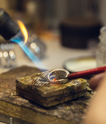 close-up-hands-jeweller-goldsmiths-making-golden-ring-with-gemstone-using-professional-tools_1